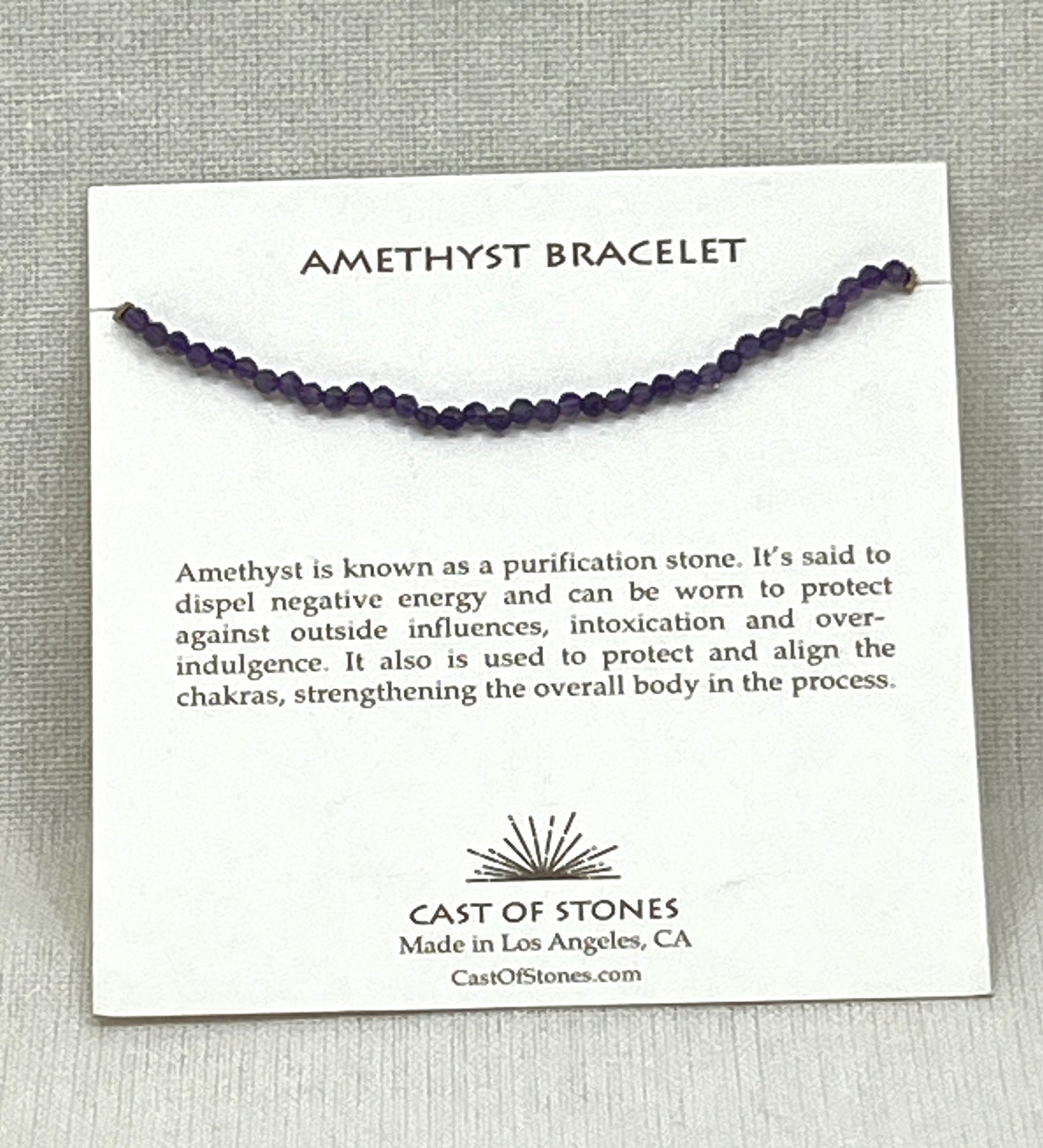 Amethyst bracelet on a card with product description and brand information, on a gray background
