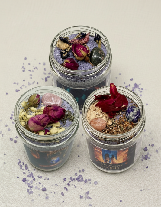 Three glass jars from the Love's Calling Collection filled with bath salts, flowers, and crystals on a white background