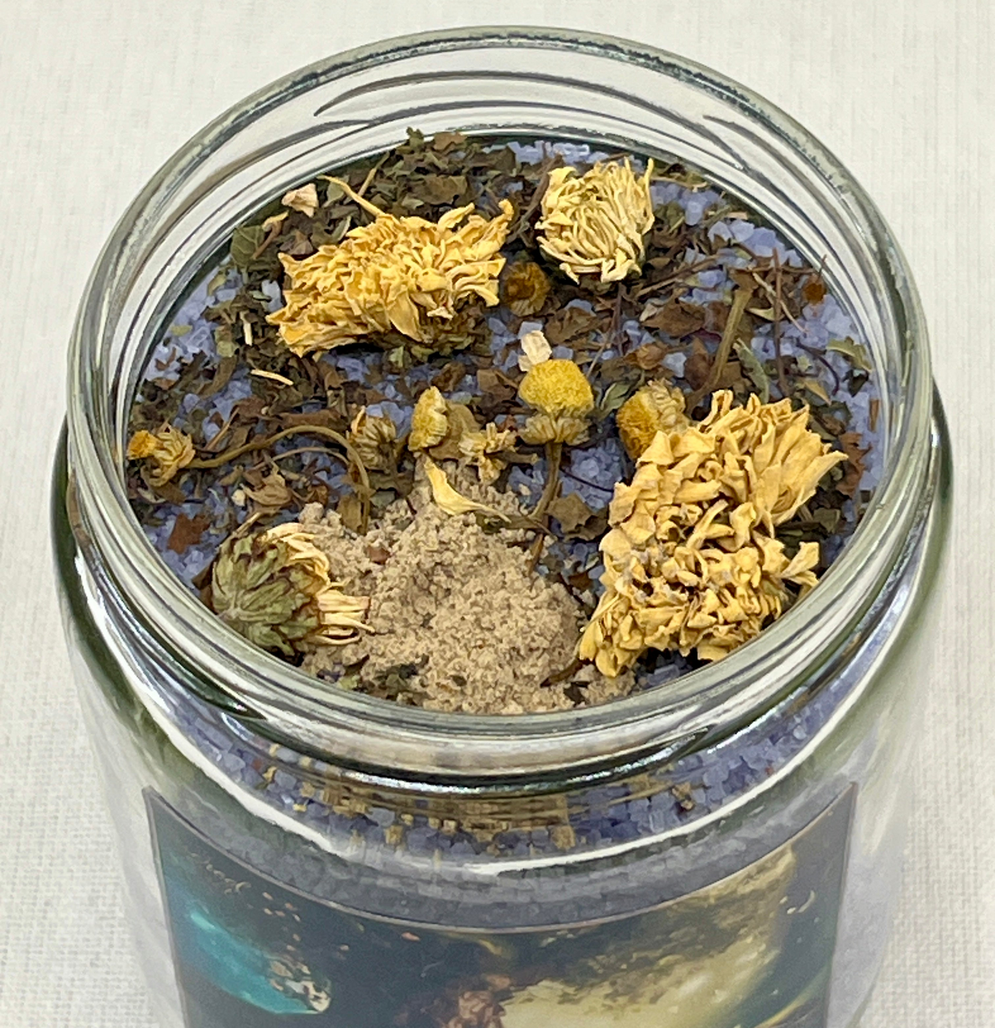 Glass jar filled with dried herbs and spices on a light background