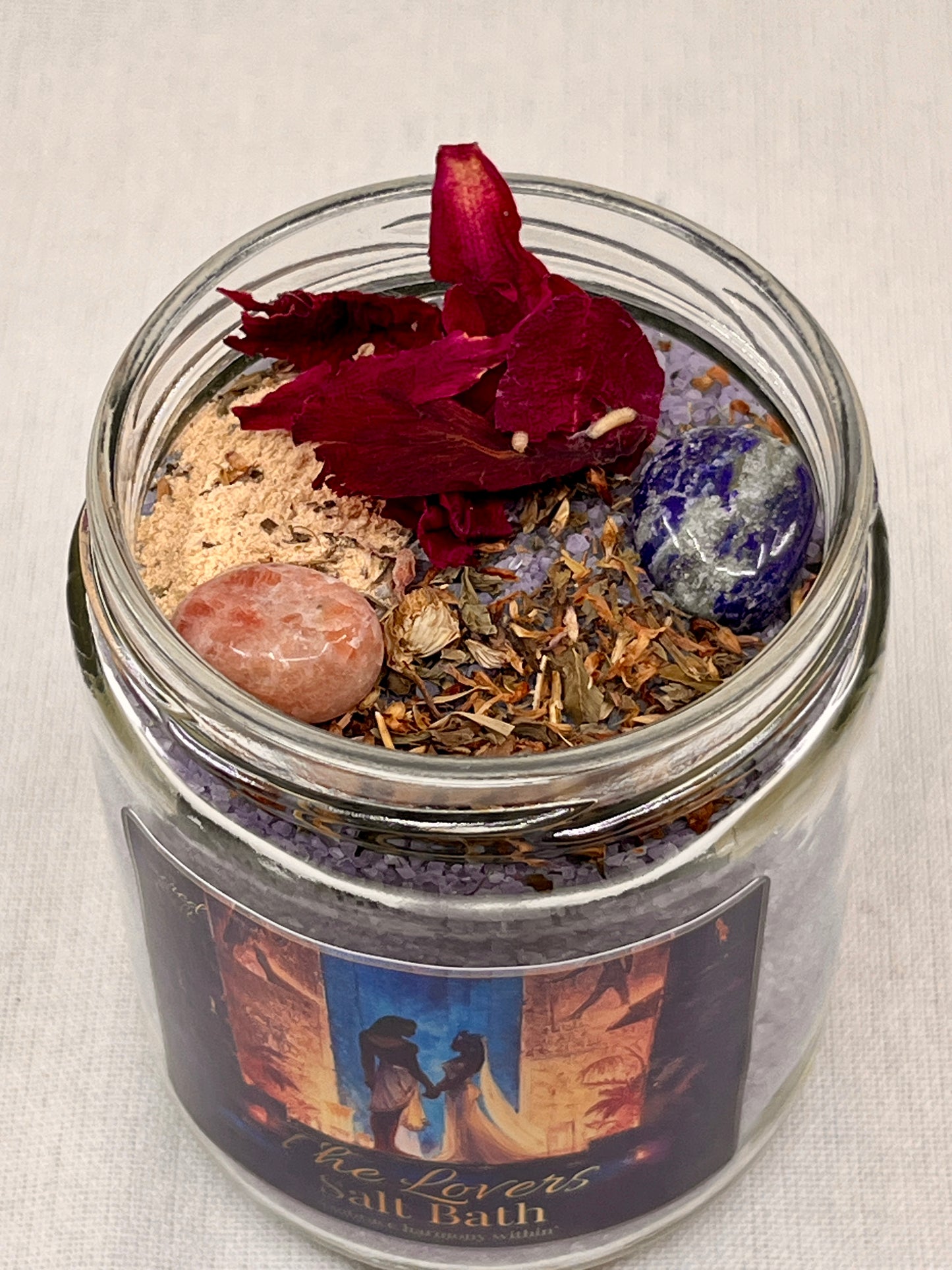 Glass jar with salt bath mix, rose petals, and crystals on a neutral background