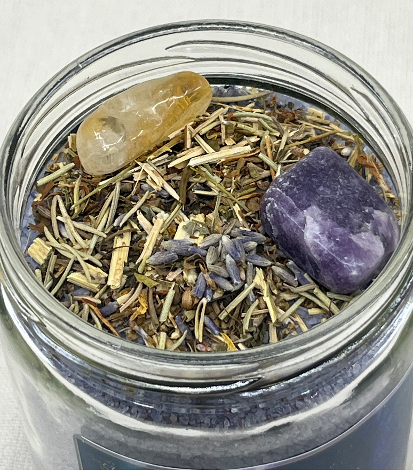 Glass jar with dried herbs and stones on a white background