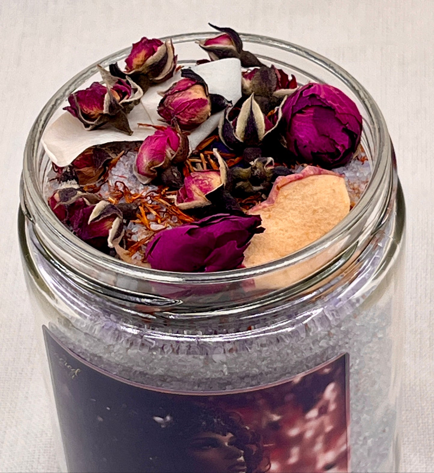 Jar filled with dried flowers and herbs on a light background