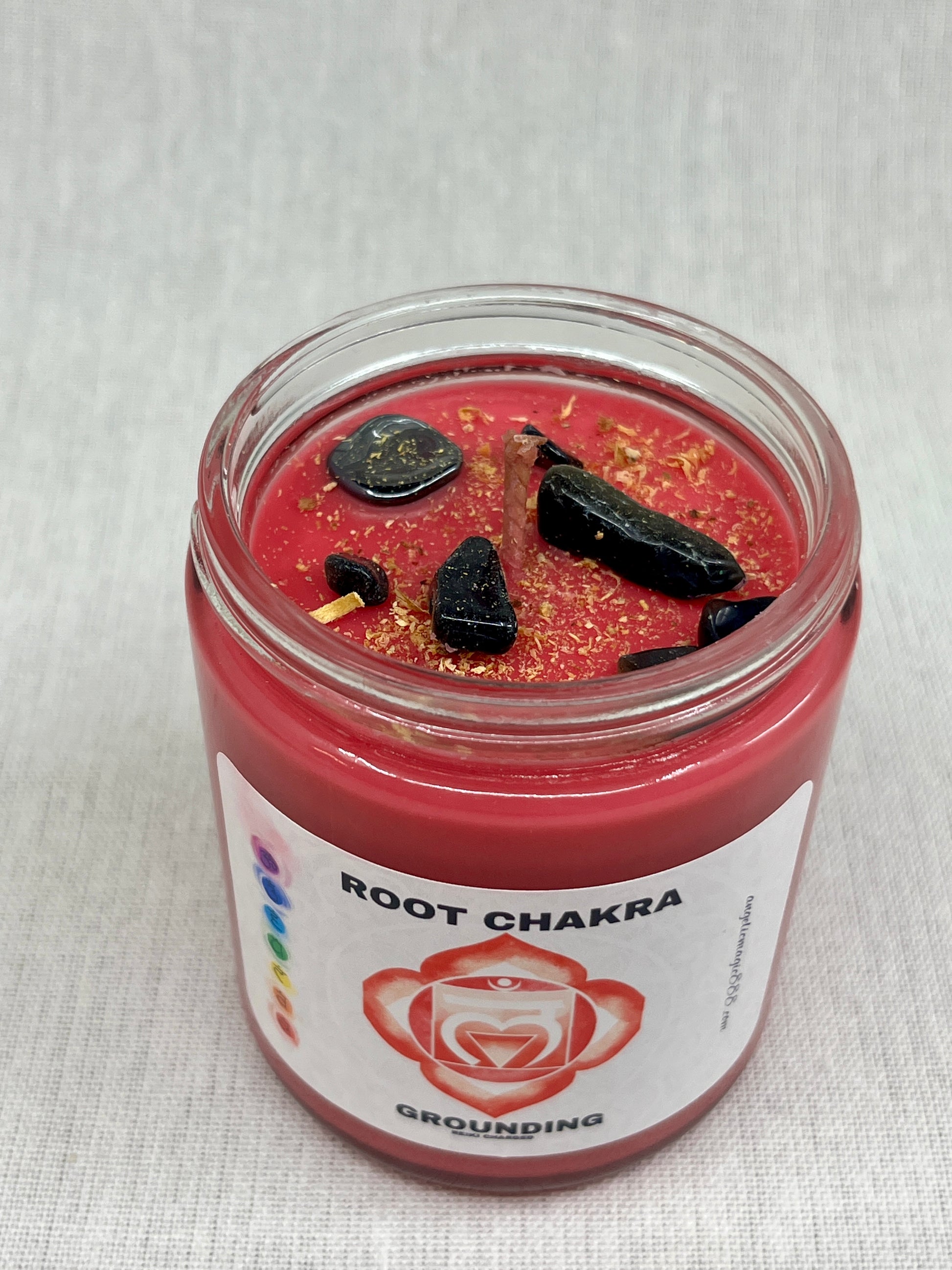 Red candle in a glass jar labeled 'Root Chakra' on a white background