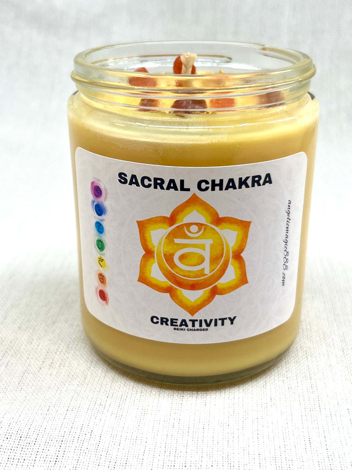 Candle in a glass jar labeled 'Sacral Chakra' with a white background