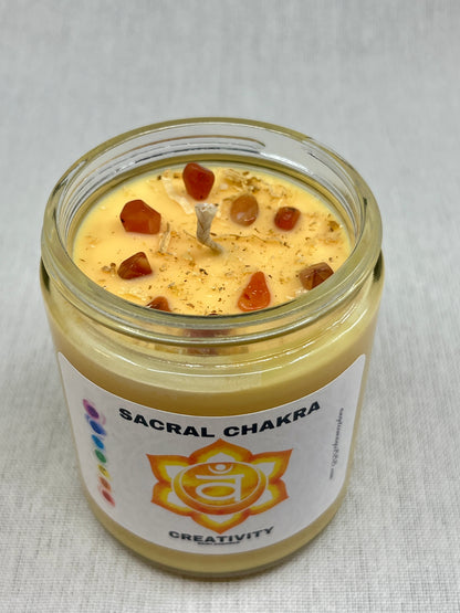 Candle in a glass jar labeled 'Sacral Chakra' with a white background
