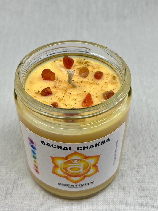 Candle in a glass jar labeled 'Sacral Chakra' with a white background