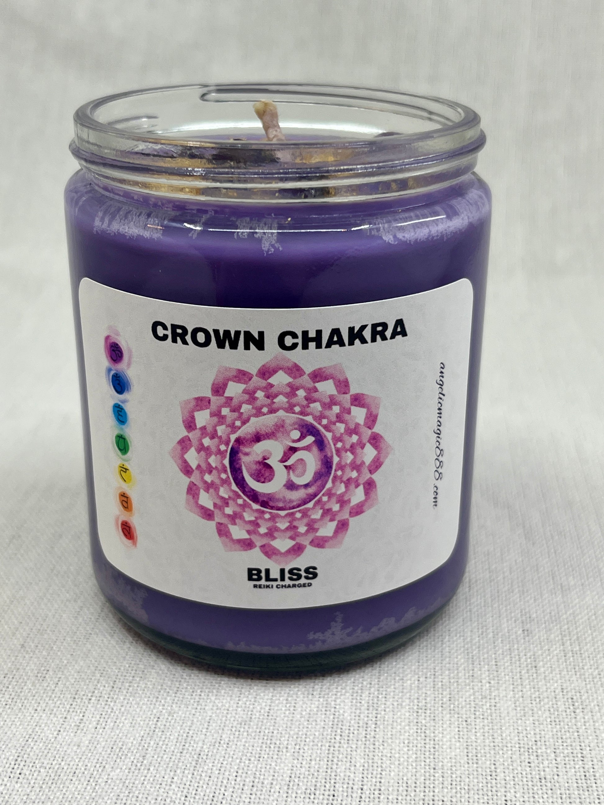 Purple candle in a glass jar labeled 'Crown Chakra' on a light gray background
