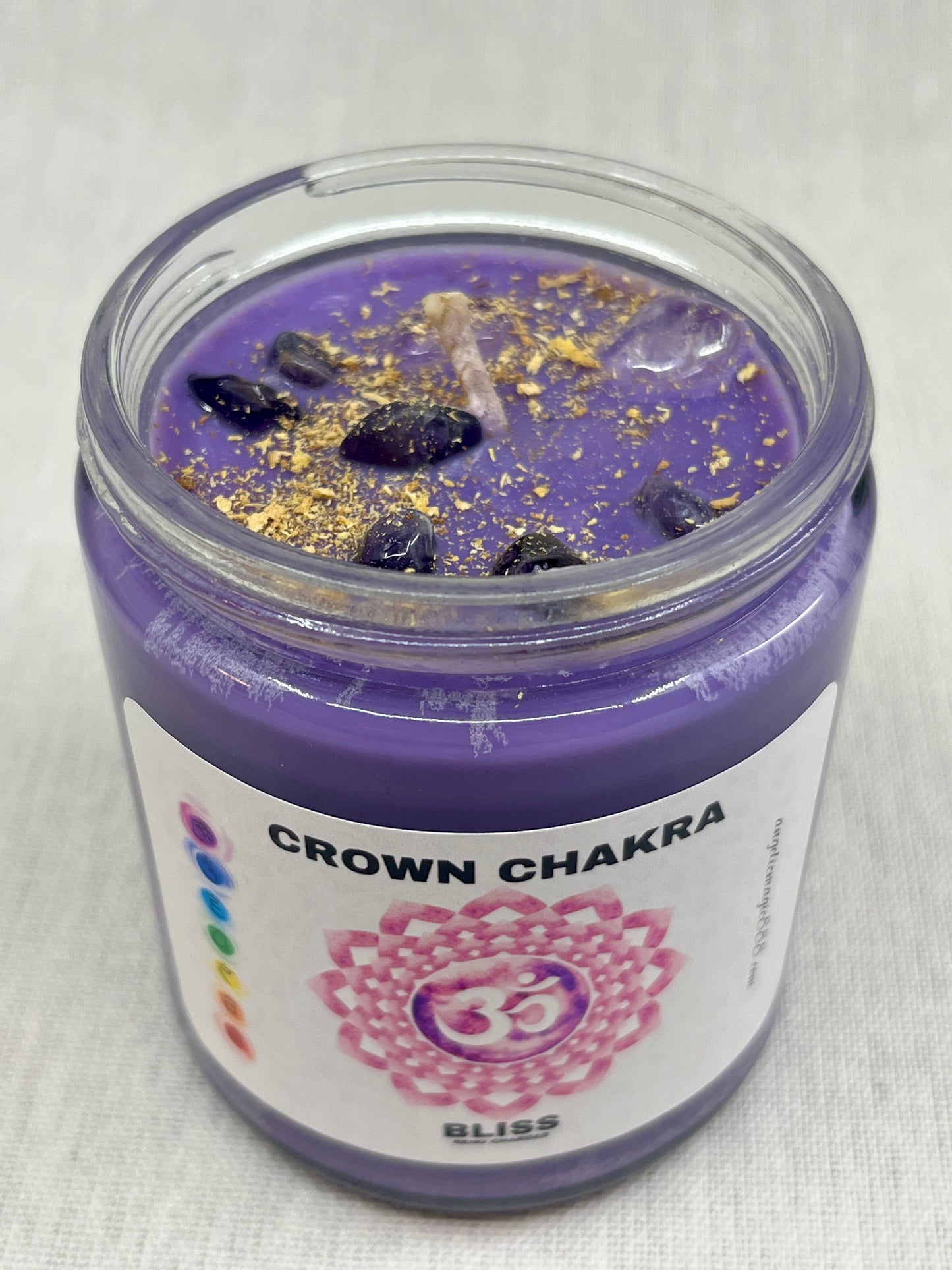 Purple candle in a glass jar labeled 'Crown Chakra' on a light gray background