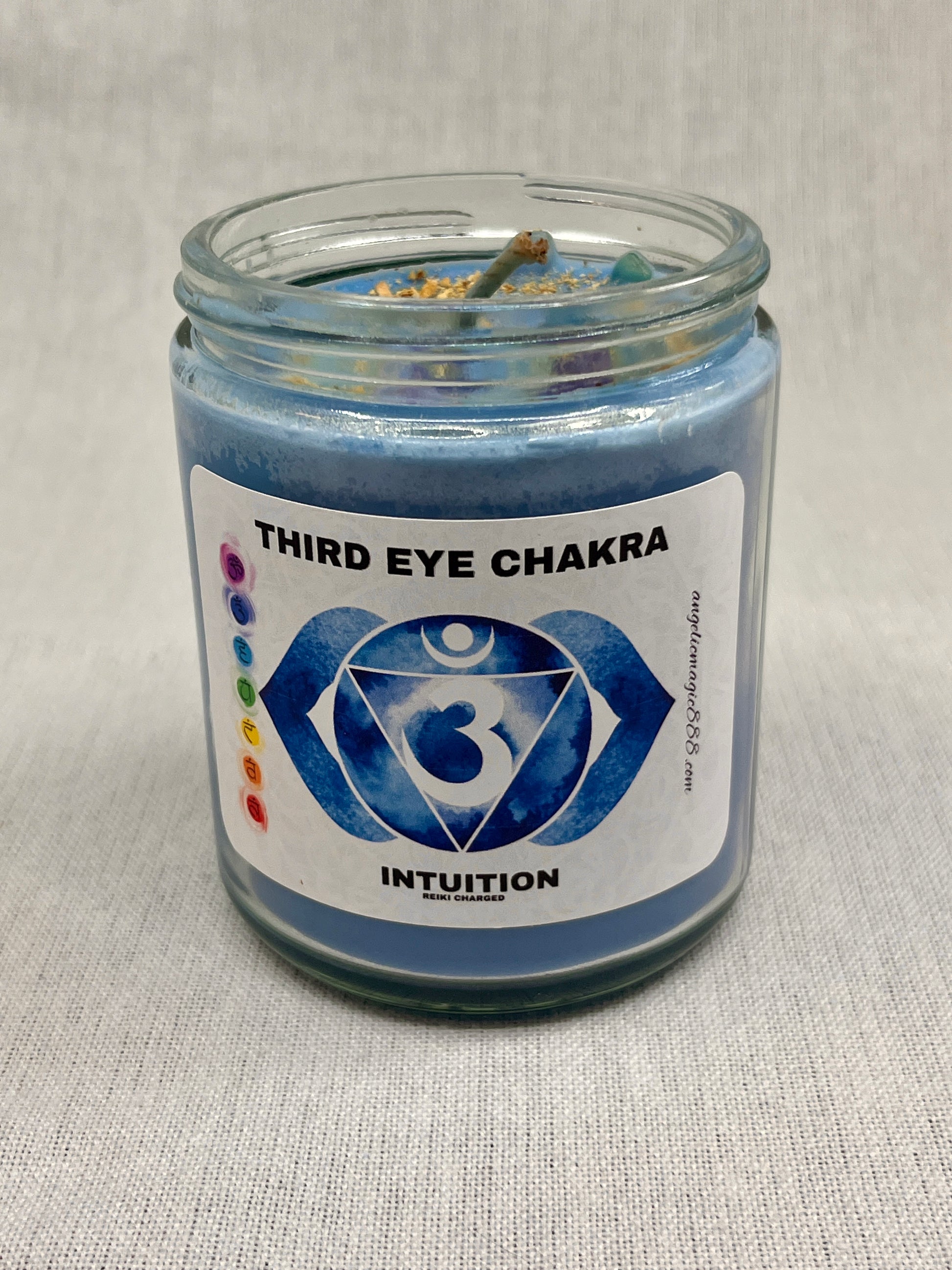 Blue candle in a glass jar with a label indicating 'Third Eye Chakra' and 'Intuition'.