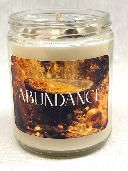 Candle in a glass jar with 'Abundance' label on a white background