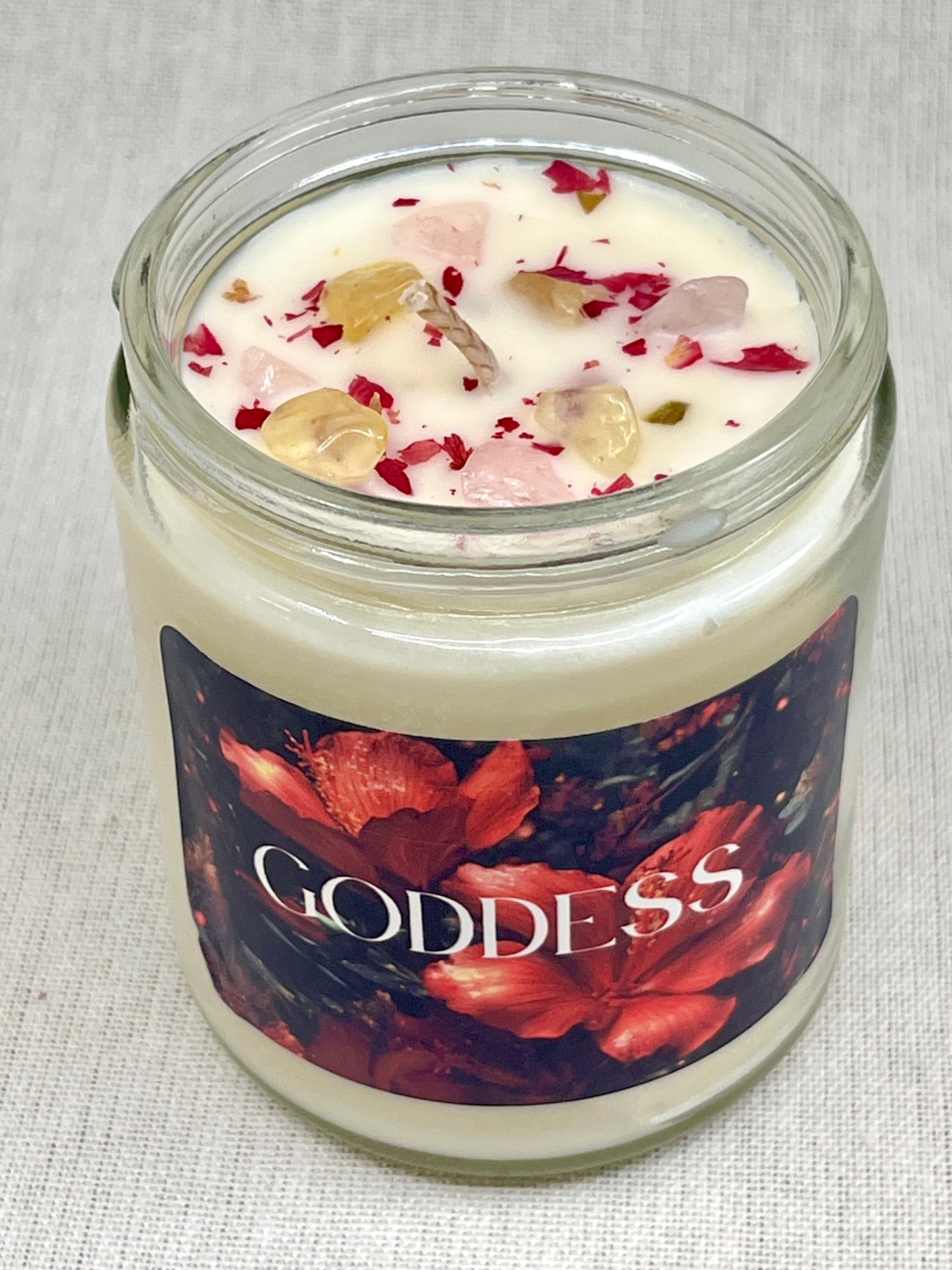 Candle in a glass jar with decorative label on a textured surface