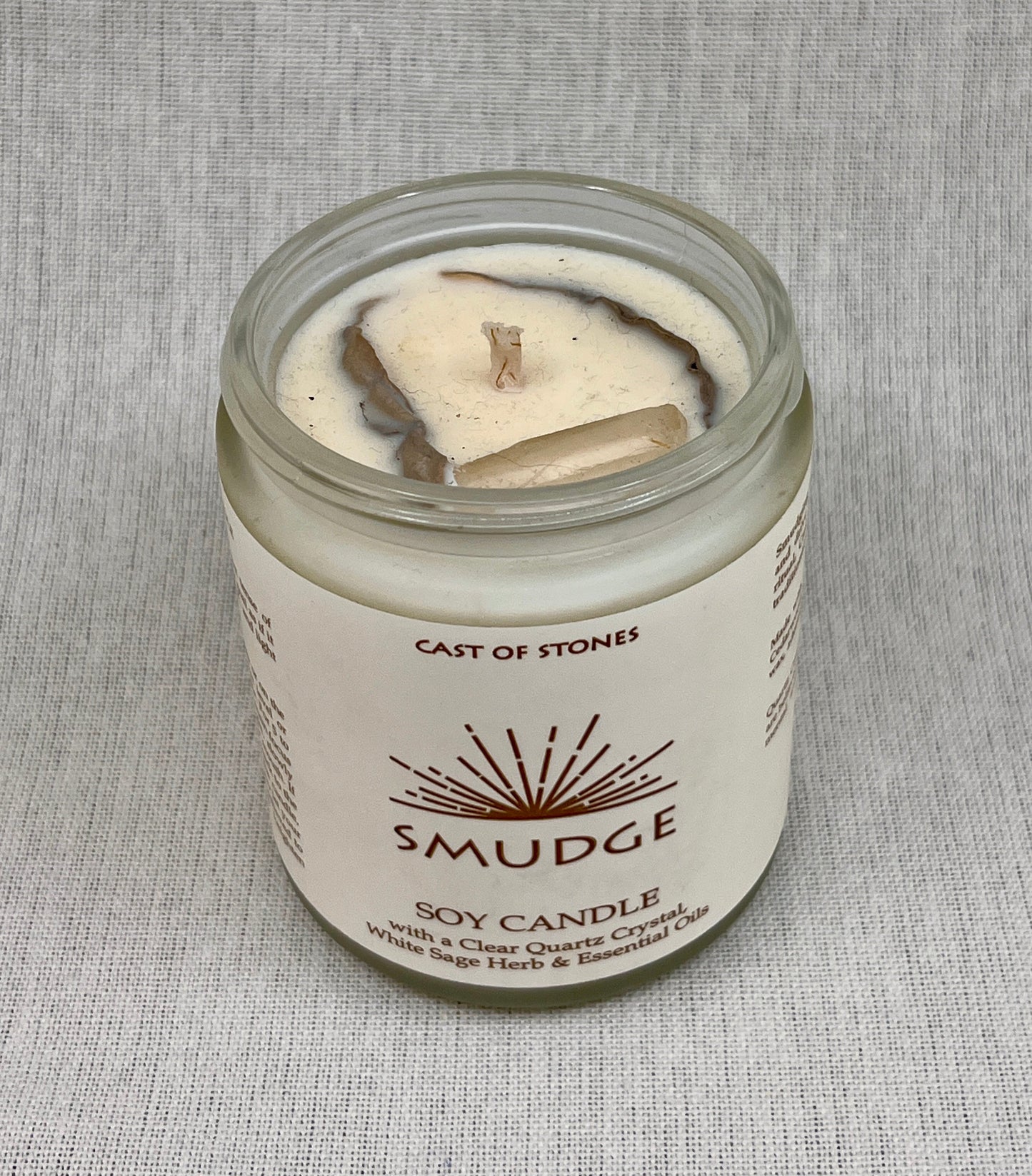 Smudge soy candle in a glass jar with a label on a gray background