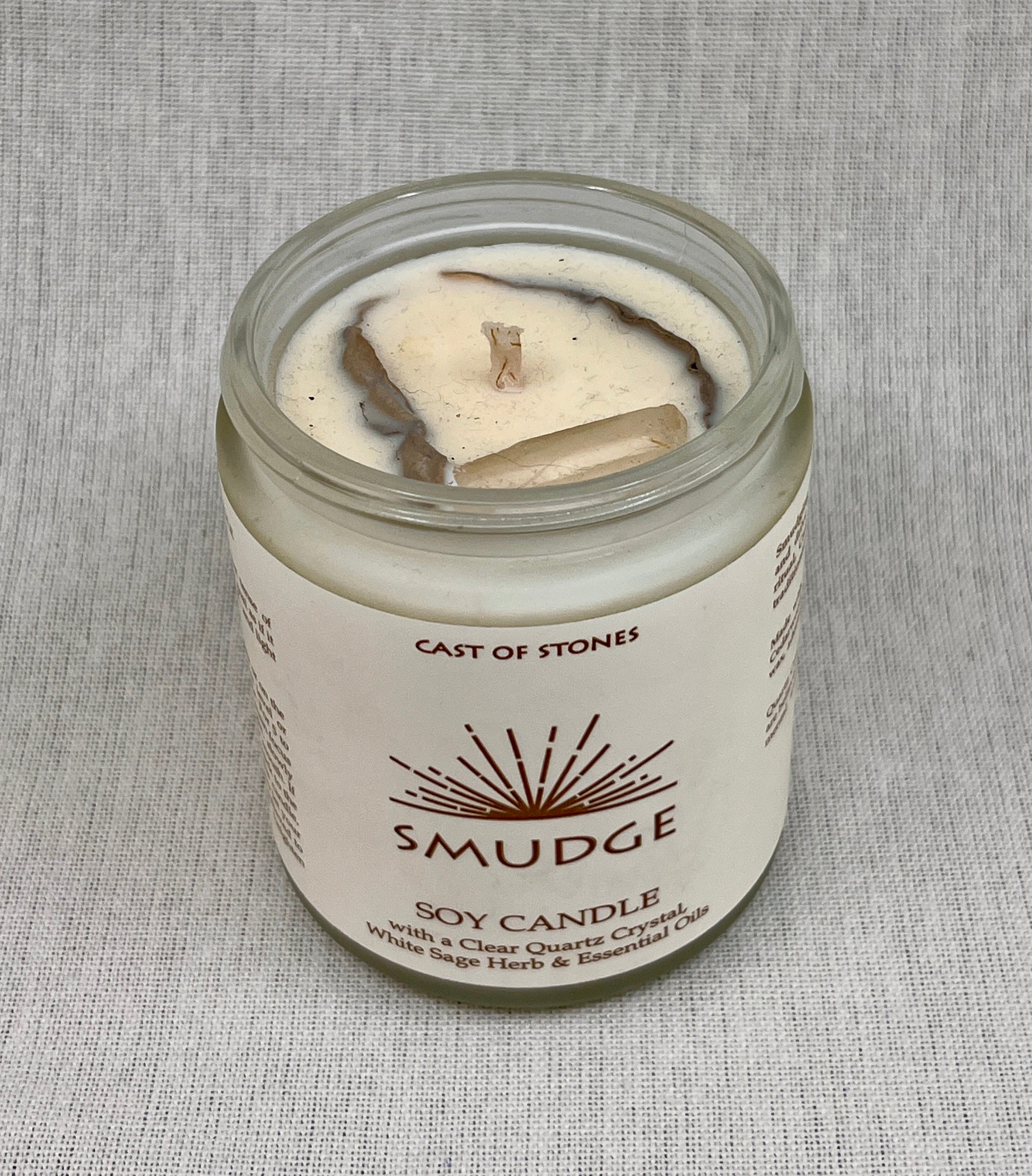 Smudge soy candle in a glass jar with a label on a gray background