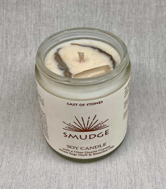 Smudge soy candle in a glass jar with a label on a gray background