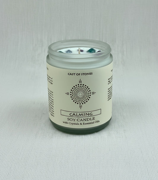 Candle jar labeled 'Cast of Stones' with a label indicating it's a 'Calming Soy Candle with Crystals & Essential Oils' on a white background.