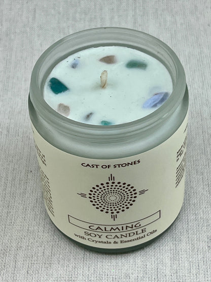 Candle jar labeled 'Cast of Stones' with visible crystals on a textured gray background