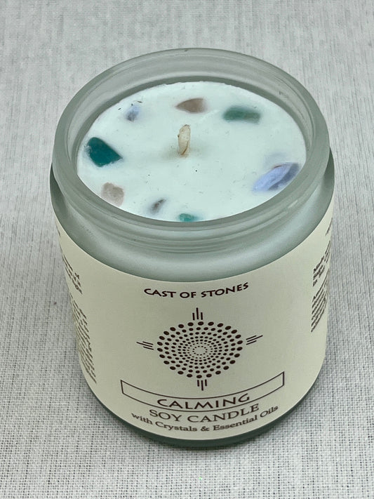 Candle jar labeled 'Cast of Stones' with visible crystals on a textured gray background