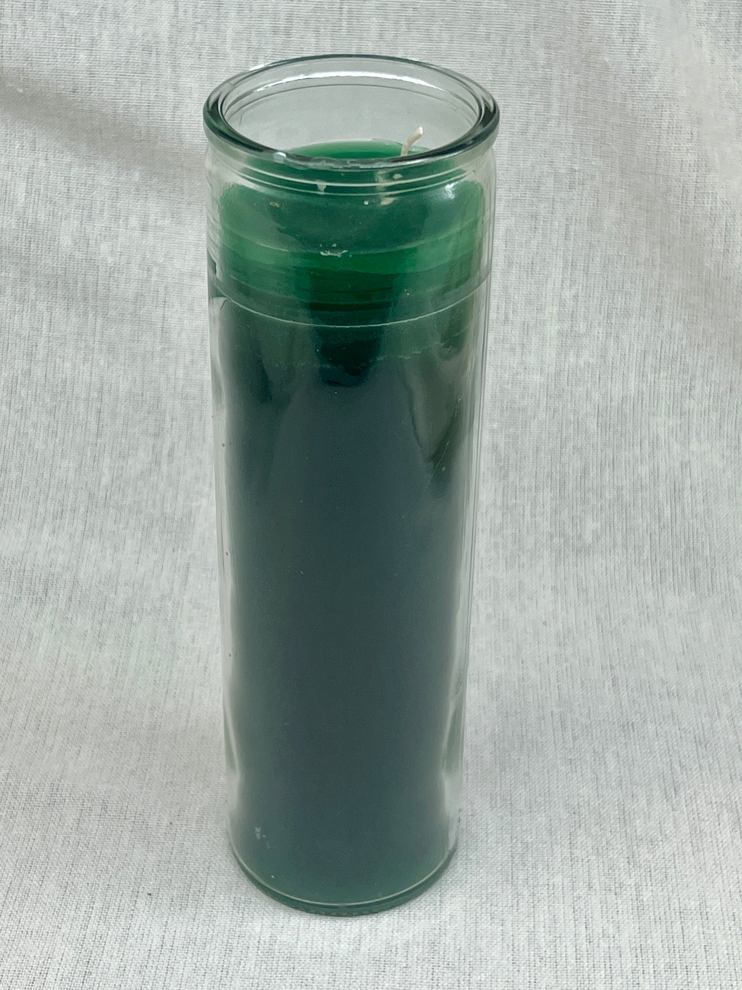 Green candle in a glass container on a light gray background