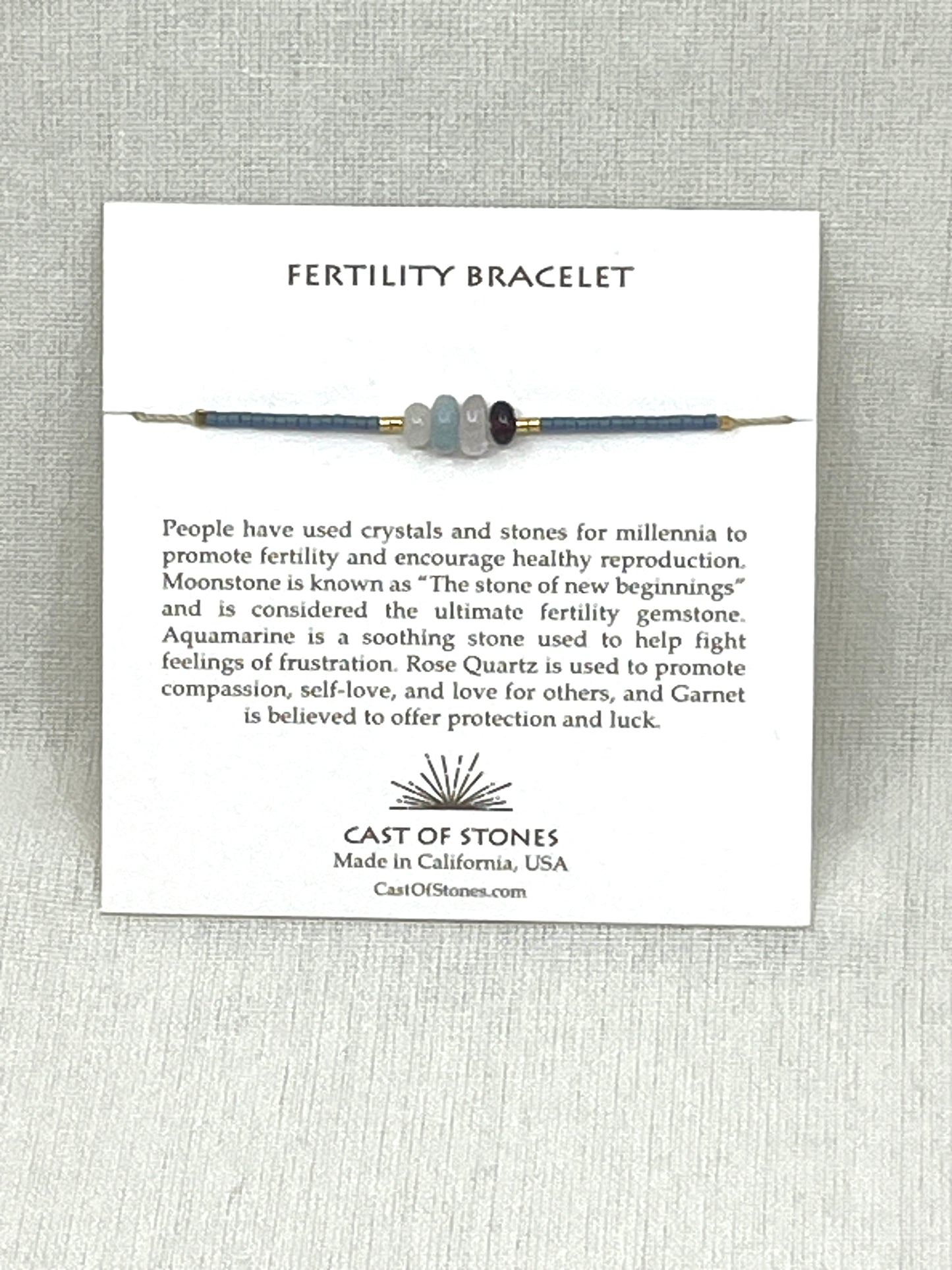 Fertility bracelet with description card on a textured gray background