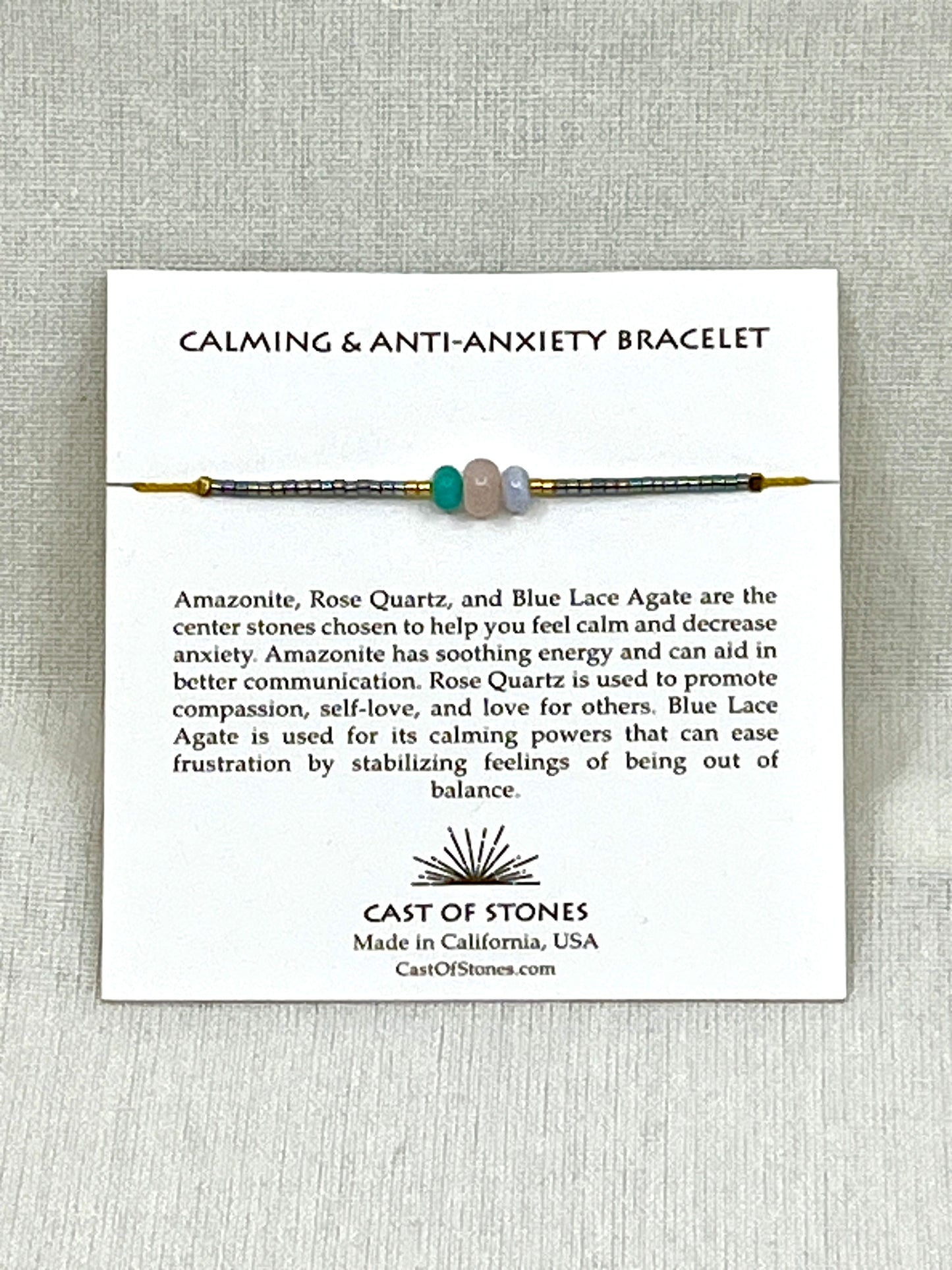 Thee stone bracelet with display card and text on a gray background