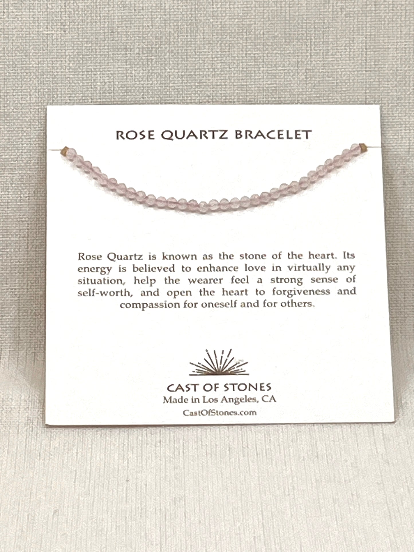 Rose Quartz bracelet on a display card with product description and brand information.