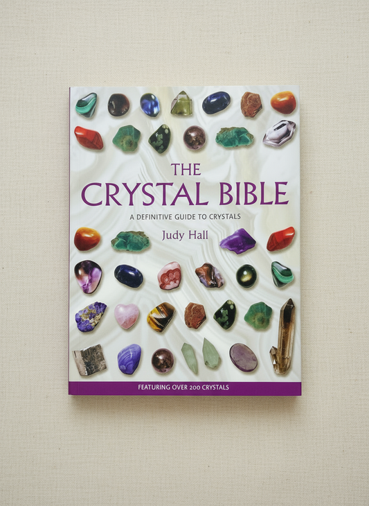 Book titled 'The Crystal Bible' by Judy Hall on a beige background