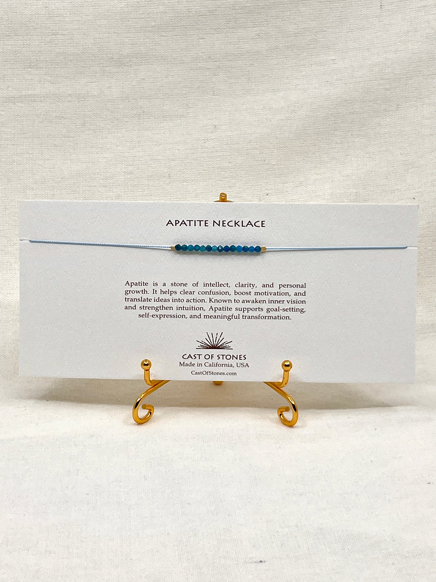 Apatite necklace on a display stand with a card detailing the stone's properties, brand name, and location.