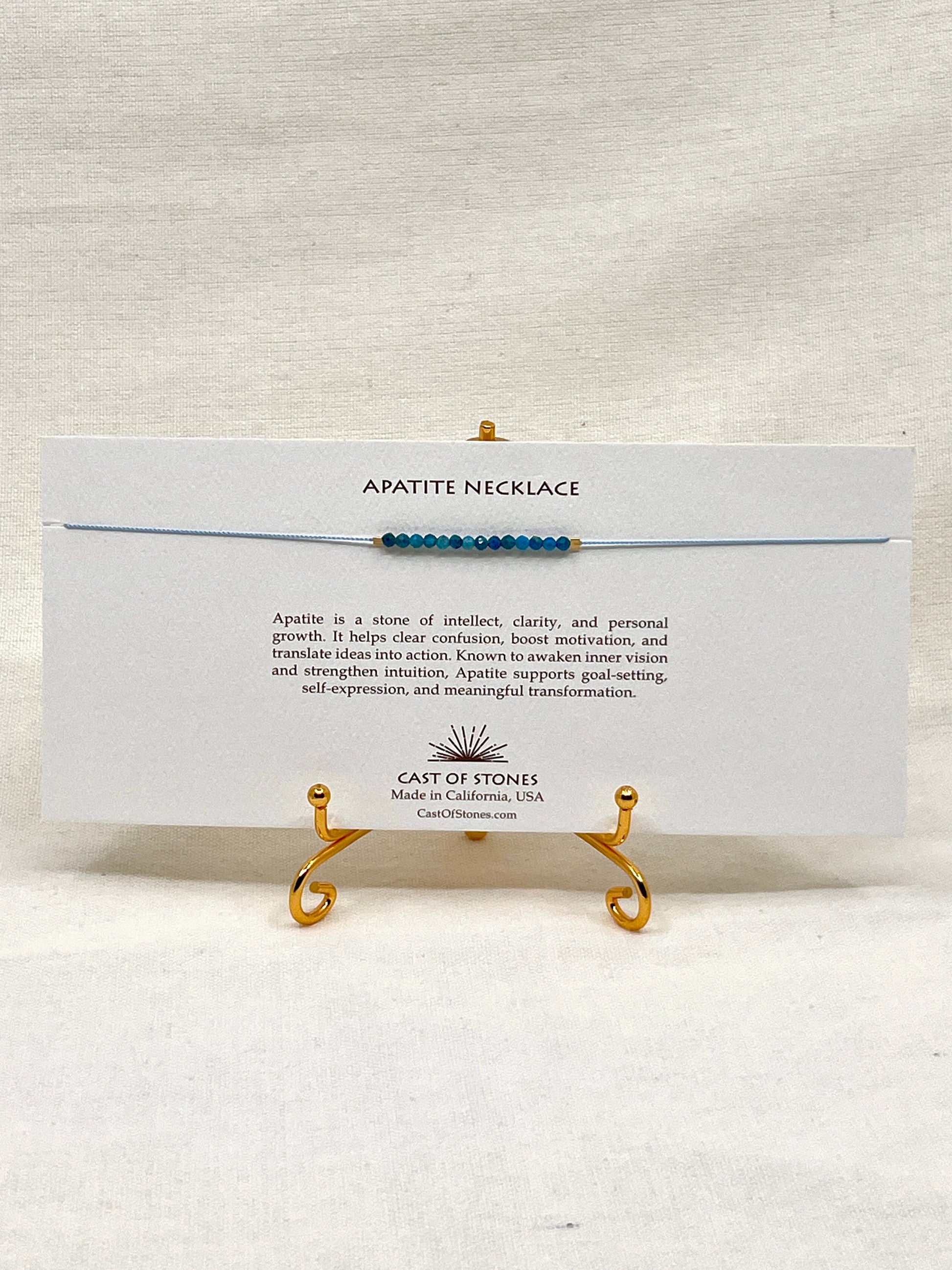 Apatite necklace on a display stand with a card detailing the stone's properties, brand name, and location.