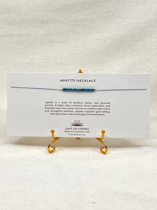 Apatite necklace on a display stand with a card detailing the stone's properties, brand name, and location.