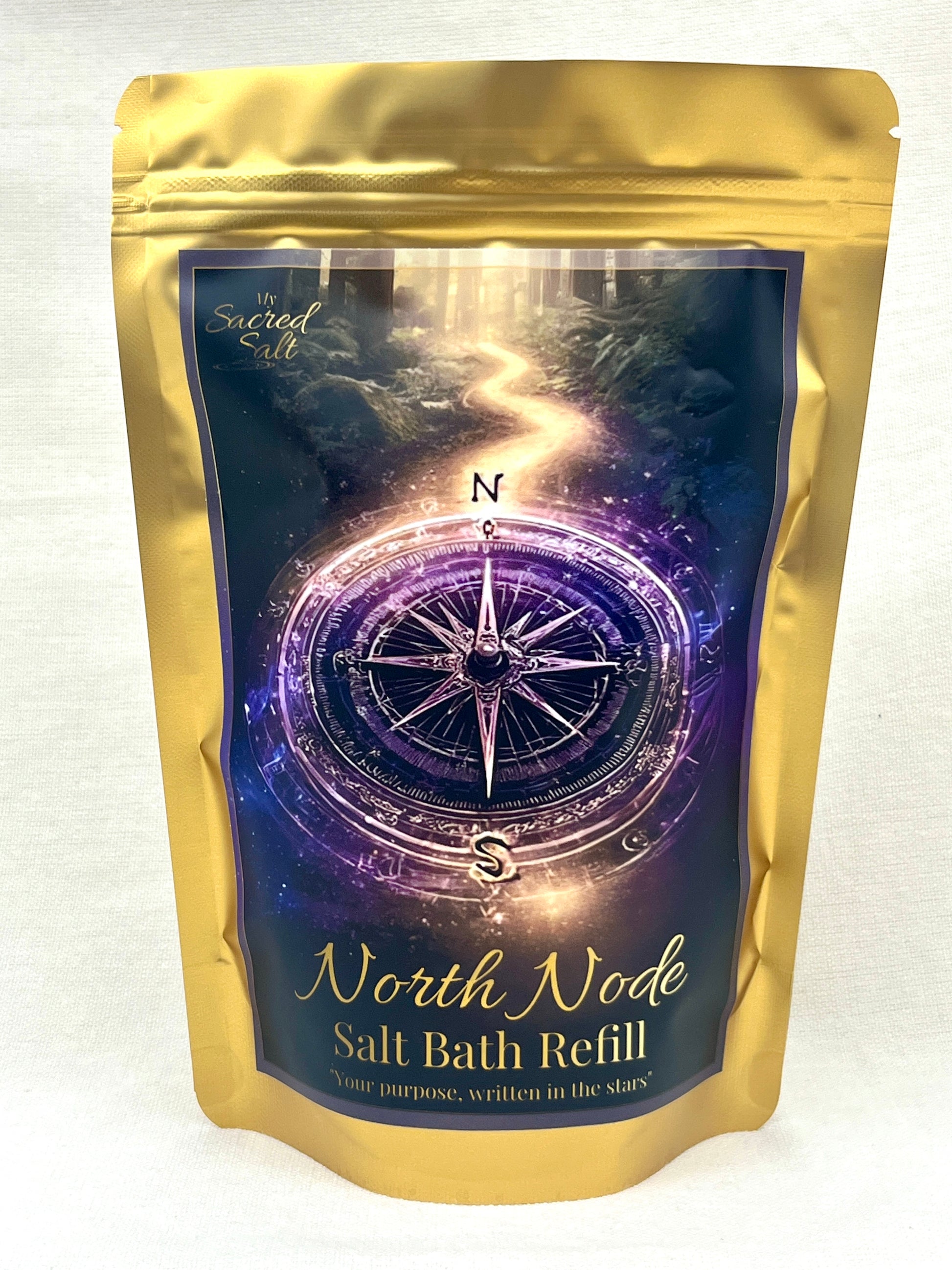 Gold packaging of North Node Salt Bath Refill with a mystical compass design on a dark background