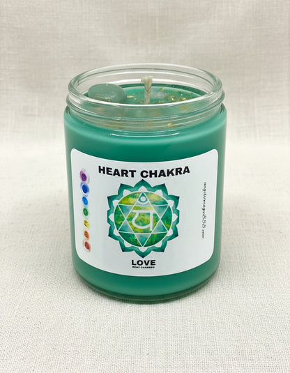 Green candle in a glass jar with a label indicating 'Heart Chakra' on a light background