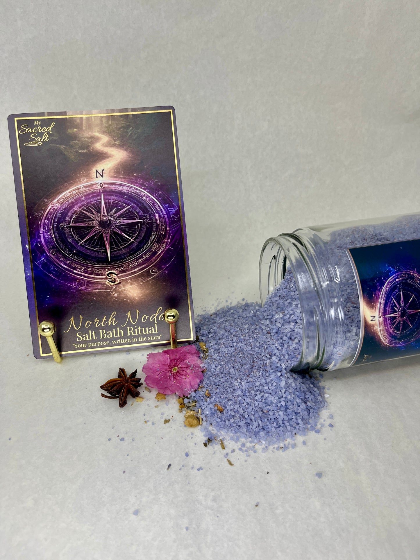 Purple salt bath ritual product with packaging and decorative elements on a light gray background