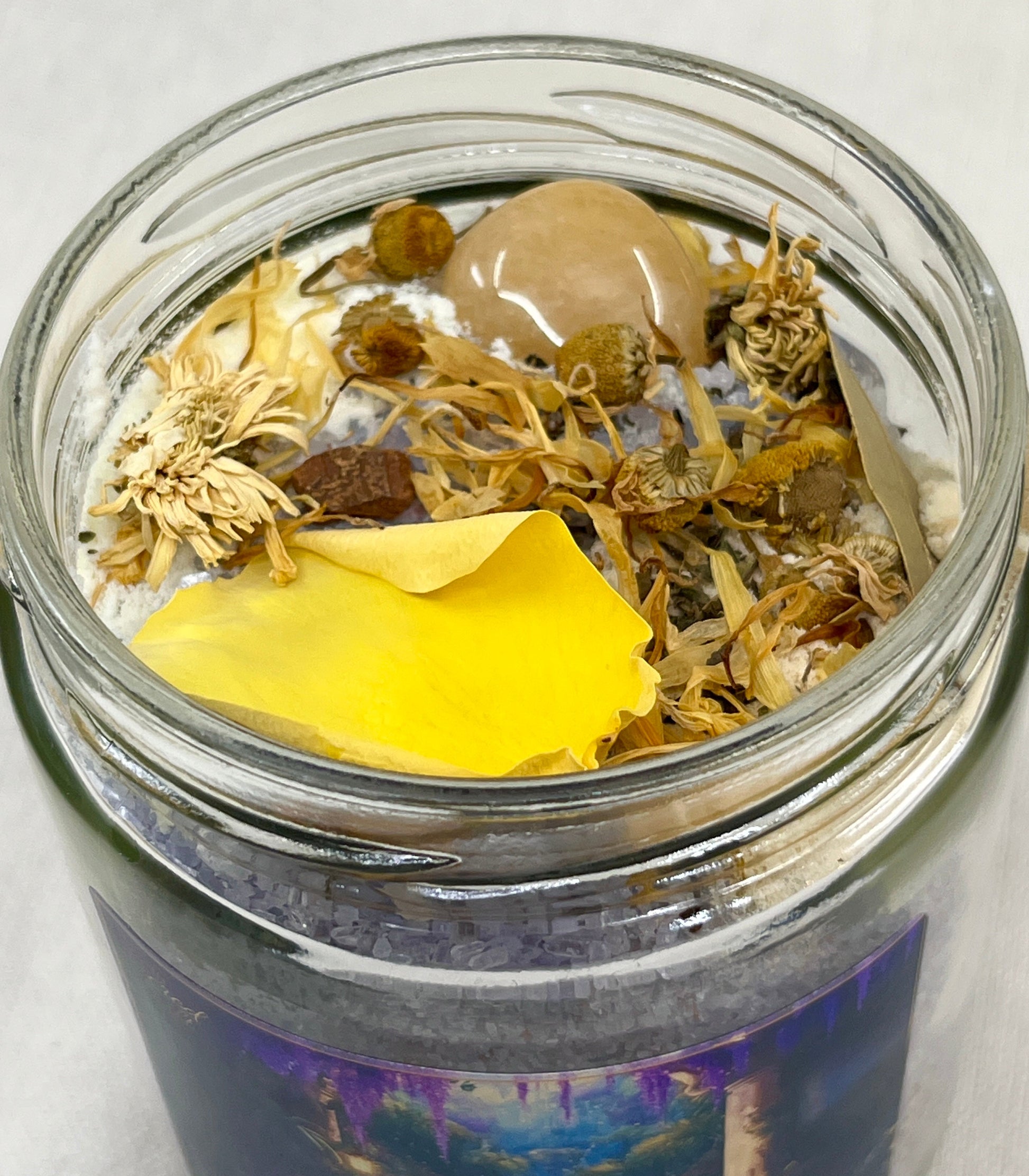 Glass jar with dried herbs and a yellow leaf on a white background