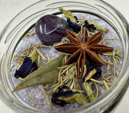 Glass jar with star anise, purple stone, and dried herbs on a textured surface