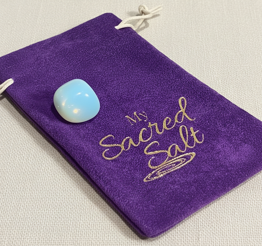 Opalite tumble stone on a purple pouch labeled 'My Sacred Salt'. on a ivory linen