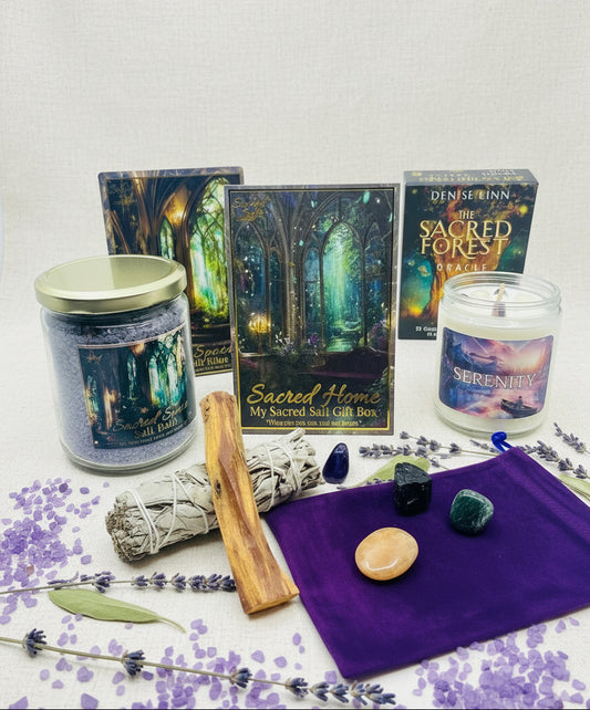 Set of items from the My Sacred Salt Sacred Home Gift Box including candles, boxes, Sacred Space Salt Bath with matching ritual card, sage and palo santo and crystals on a white surface with a purple crystal pouch. Purple salts and dried botanicals surround the display