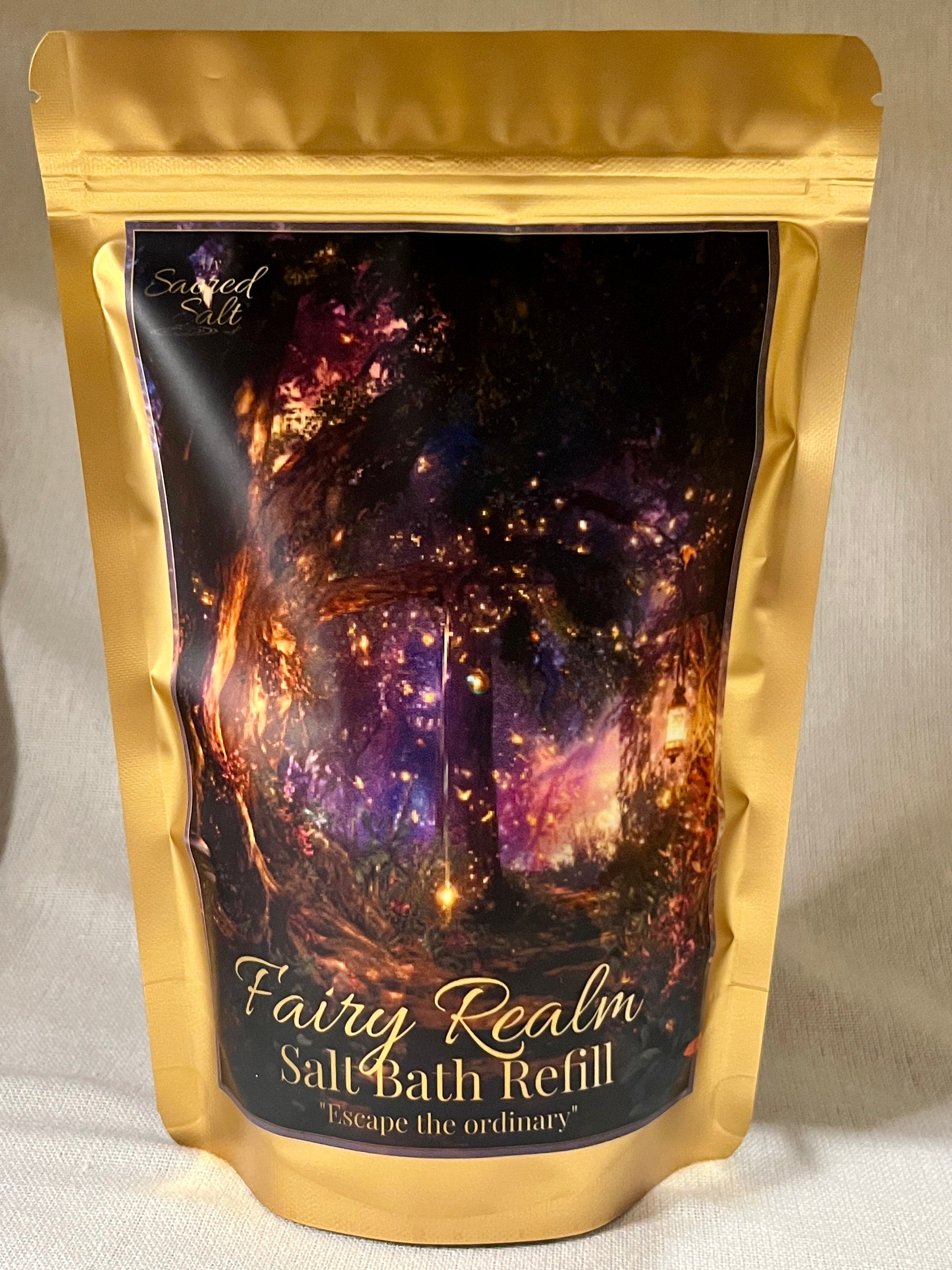 Gold packaging of Fairy Realm Salt Bath Refill with a mystical forest design on a glittering background