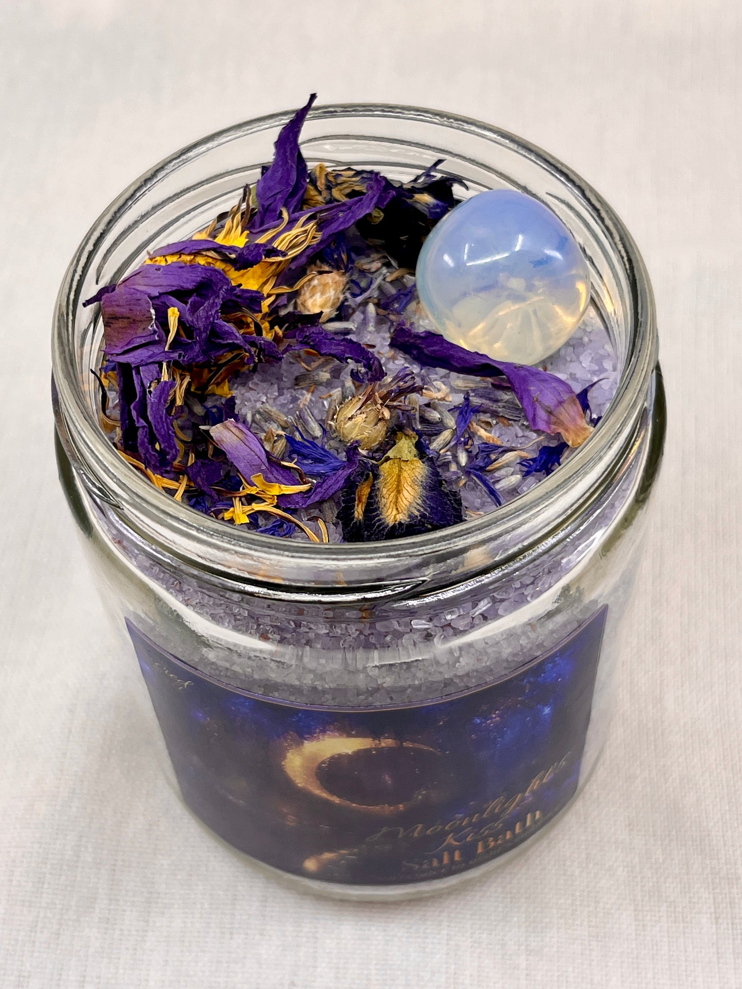 Glass jar with bath salts and purple flowers on a white background