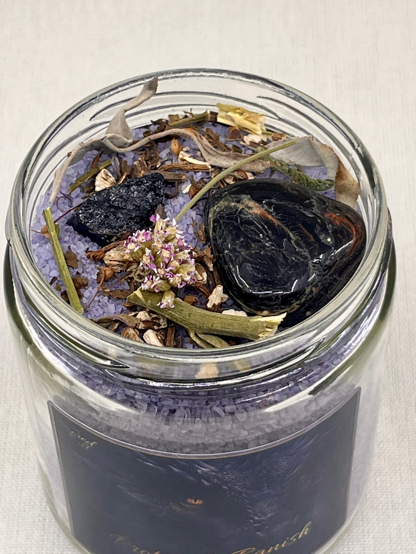 Glass jar with dried herbs and crystals on a light background