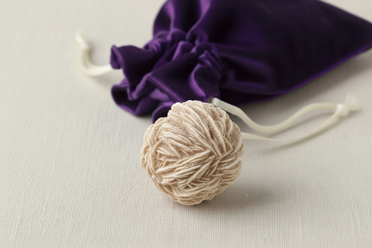 Beige decorative item with a purple drawstring bag on a light gray background
