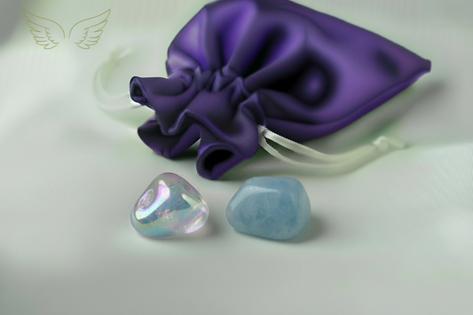 Two colorful stones on a white surface with a purple fabric pouch in the background.