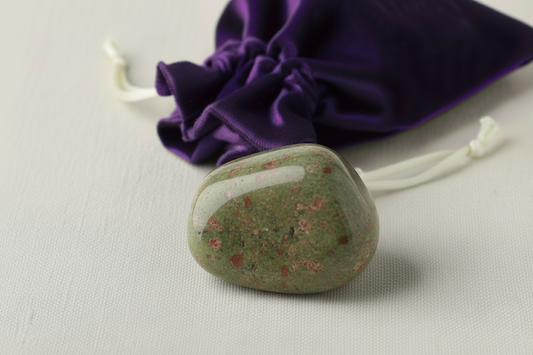 Green stone with a purple drawstring bag in the background.