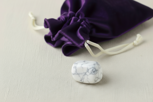 Marble-textured stone on a beige surface with a purple drawstring bag in the background