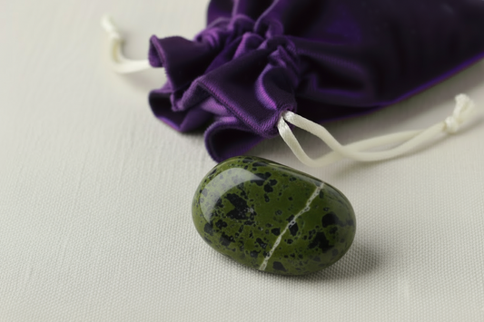Green stone with a purple drawstring bag in the background.