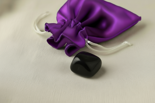 Purple satin drawstring bag with a black stone on a beige background