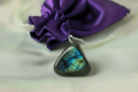 Labradorite stone with a purple fabric bag in background