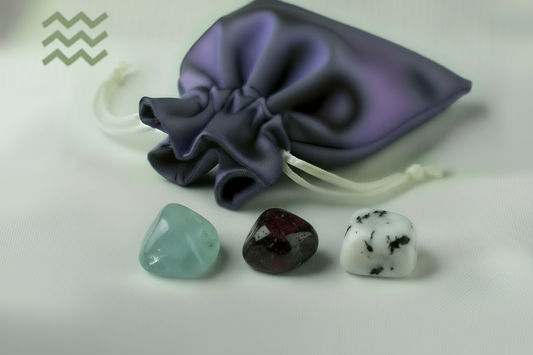 Three crystals on a white surface with a purple drawstring bag in the background.