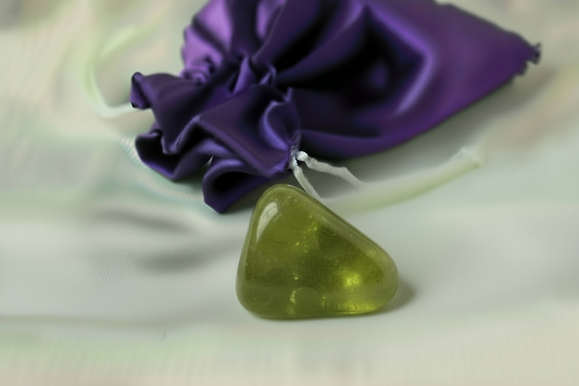 Green triangular stone on a white surface with a purple fabric in the background