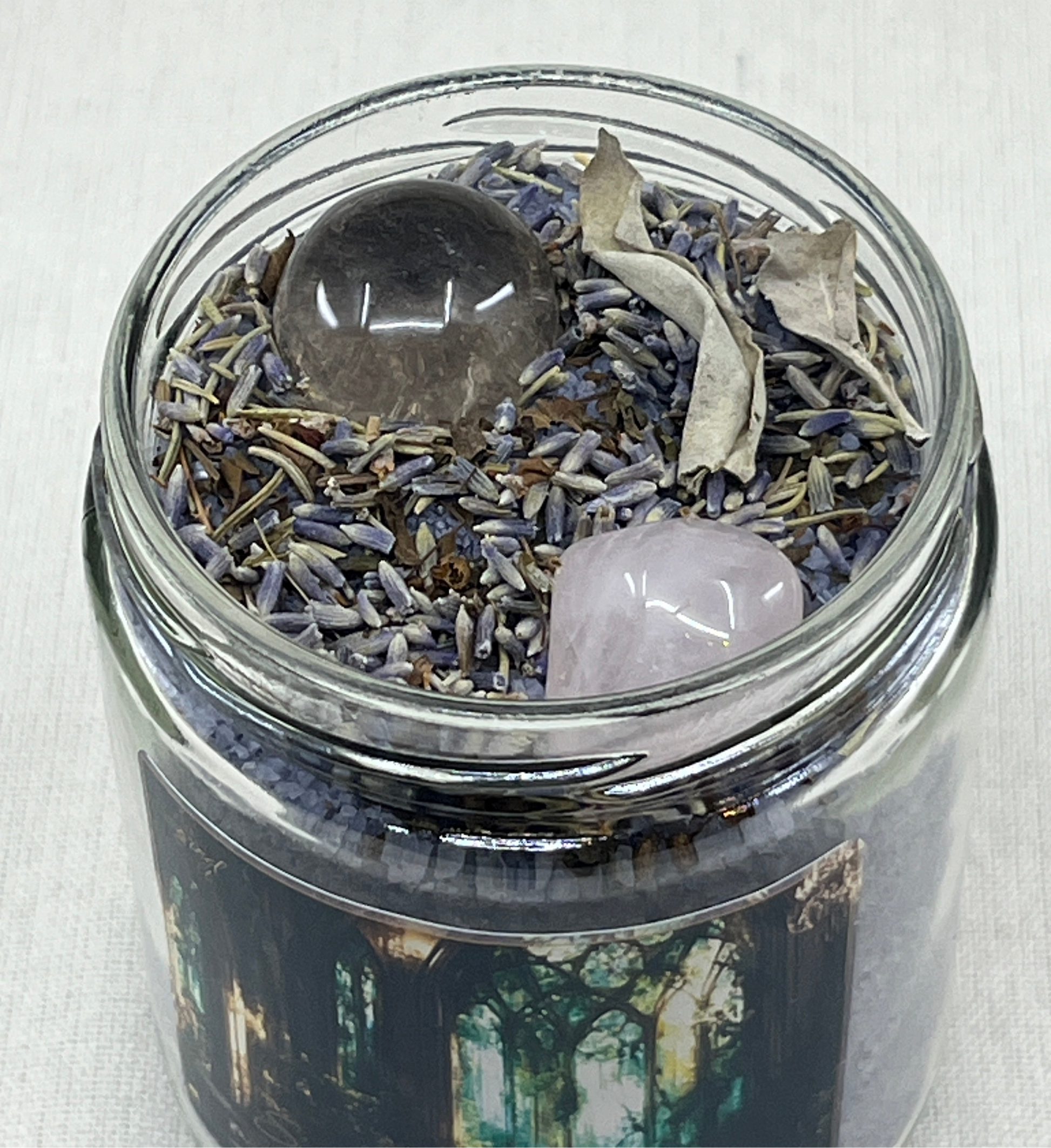 Glass jar with lavender, crystals, and a wooden stick on a white background