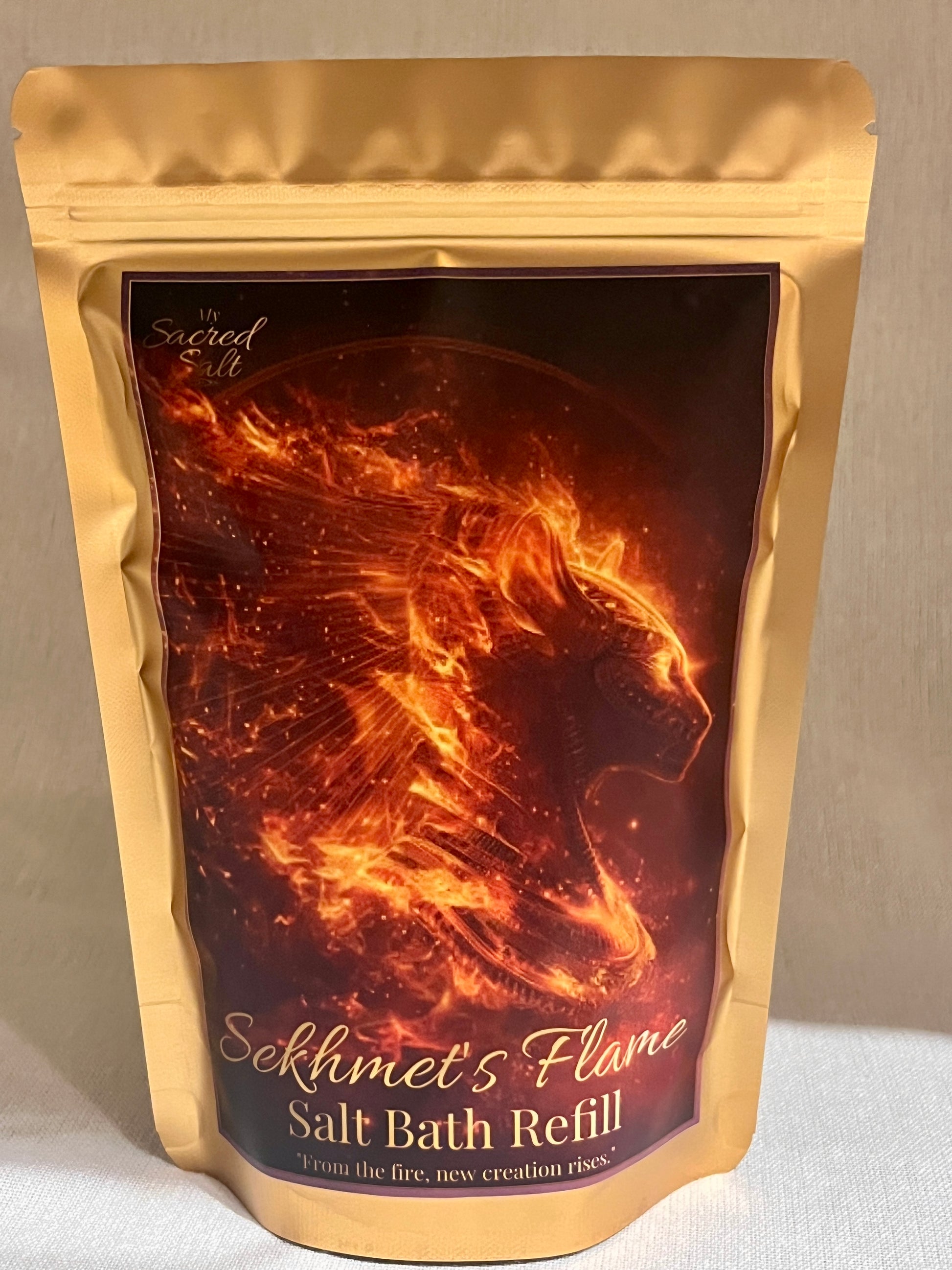 Gold packaging of Sekhmet's Flame Salt Bath Refill with a fiery Egyptian cat design on a dark background